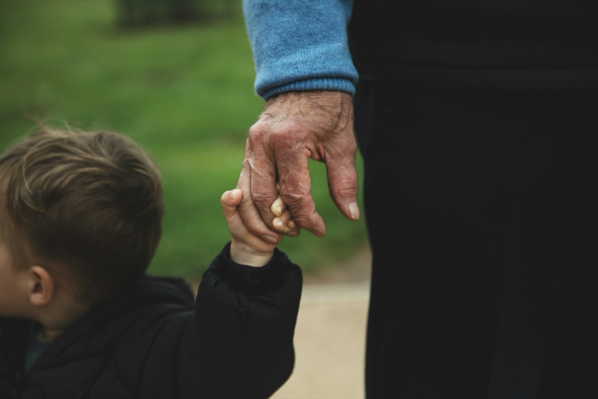 A small child's hand holding an older person's hand as they walk together